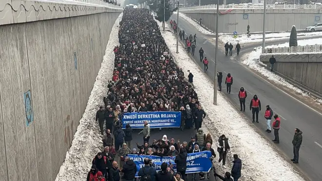 Diyarbakır'da Suriye'deki Kürtlerin yoğun olarak yaşadığı mahallelerde yaşanan şiddetin protesto edildiği yürüyüşte karlı otoyolda pankartlarla yürüyen kalabalık görülüyor.