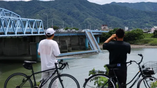 2026年7月29日，日本熊本縣八代市，兩名男士停下腳踏車眺望一座因熊本縣6.8級地震而受損的橋樑