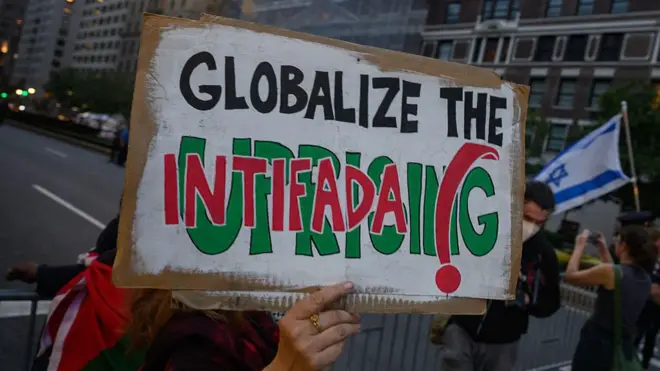 Пропалестинский участник протеста держит плакат с надписью «Глобализуй интифаду» во время антиизраильской демонстрации возле отеля премьер-министра Биньямина Нетаньяху во время 80-й сессии Генеральной Ассамблеи ООН (ГА ООН) 25 сентября 2025 года в Нью-Йорке. 