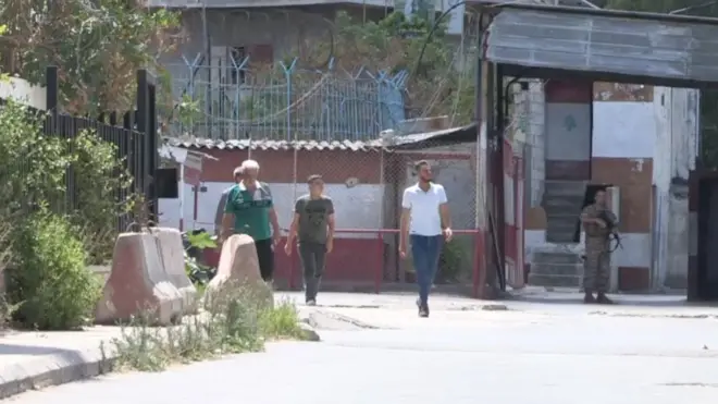 شبان من المخيم يمرون بجوار جندي لبناني عند مدخل المخيم