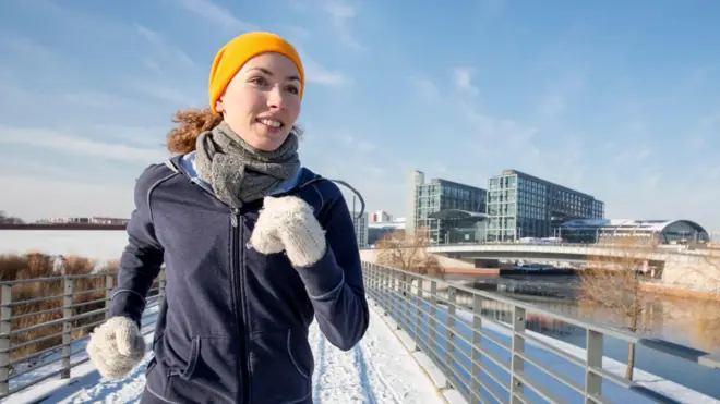 жінка в рукавичках що бігає на снігу