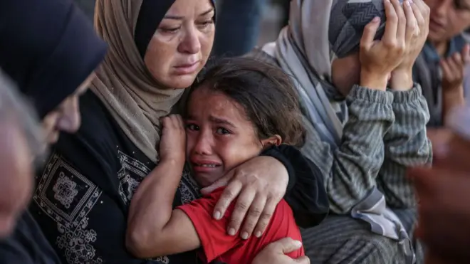 سيدة تحتضن طفلتها التي تبكي في قطاع غزة