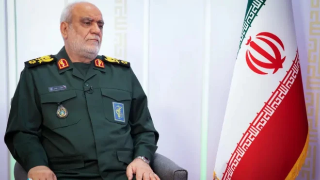 Head of Iranian Revolutionary Guards Intelligence Organisation Majid Khademi on military uniform, wit iran flag beside am