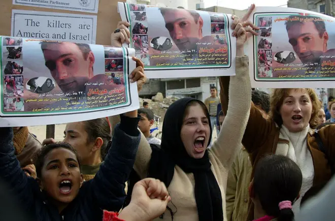 تظاهرة لأطفال فلسطينيين مع نشطاء في ذكرى مقتل توم هرندل في مخيم رفح للاجئين، جنوب قطاع غزة، في 16 يناير/كانون الثاني 2004