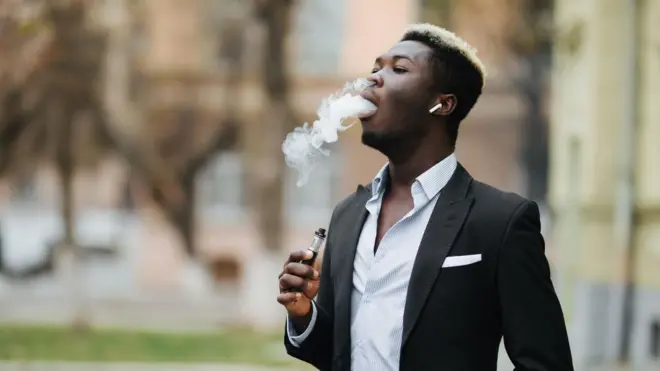 Ọkunrin to wọ aṣọ dudu ati funfun to n mu siga