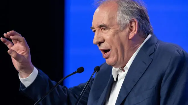 Франсуа Байру говорит в микрофон, жестикулируя правой рукой