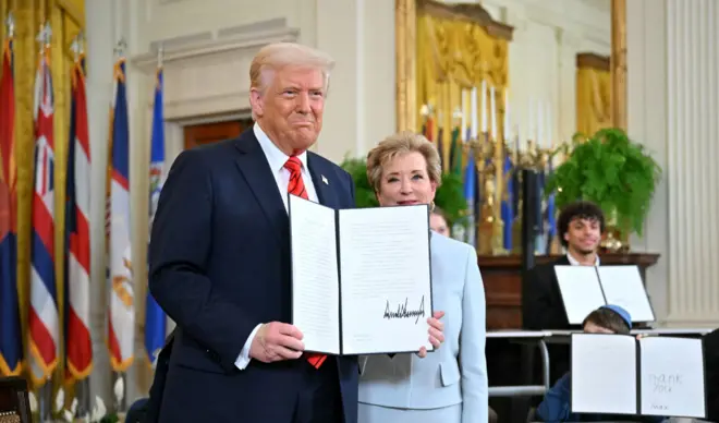 Tổng thống Donald Trump giơ sắc lệnh hành pháp vừa ký, đứng cạnh ông là Bộ trưởng Giáo dục Linda McMahon