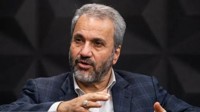 نادر یاراحمدی، با کت و شلوار و در حالیکه دستانش را تکان داده صحبت می‌کند