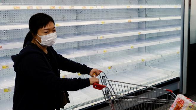 A customer wearing a face mask shops in front of partially empty shelves at a supermarket, ahead of mass coronavirus disease (COVID-19) testing, in Hong Kong, China March 4, 2022.