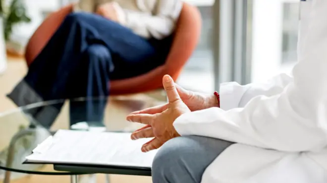 Bir doktor bir hastasıyla oturuyor ve konuşuyor. Göğüs aşağısını görüyoruz.