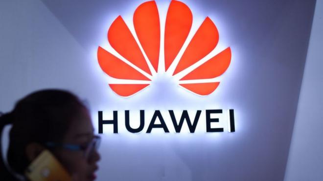 Logo de Huawei con mujer desenfocada en primer plano.