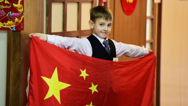 Un niño ruso sostiene una bandera nacional china durante la final en un Instituto Confucio.