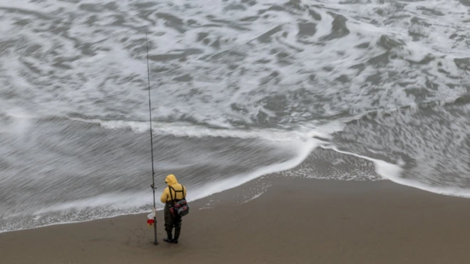 የባሕር ማዕበል እና ከዳር ላይ የቆመ ሰው