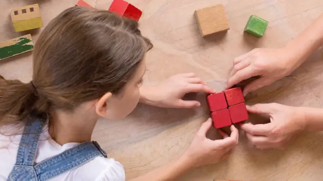 Young girl connecting wooden bricks - representative stock photo 