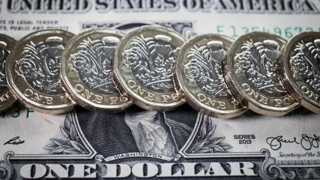 Row of new pound coins on one dollar bill