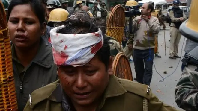 गोरखा जनमुक्ति मोर्चा समर्थकों के साथ संघर्ष में घायल हुई महिला पुलिसकर्मी की मदद करते साथी पुलिसकर्मी