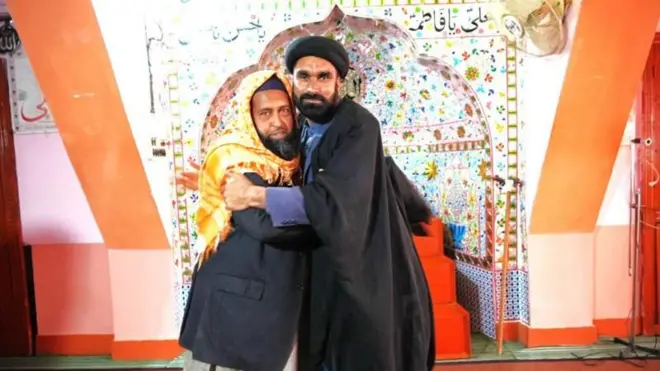 પીરાના સહિયારી મસ્જિદ (જમણે) ખાતે શિયા મુલ્લા સૈયદ મઝહર અલી અબ્બાસ પાડોશી મસ્જિદના સુન્ની મુલ્લા મુહમ્મદ શકીલને ભેટે છે