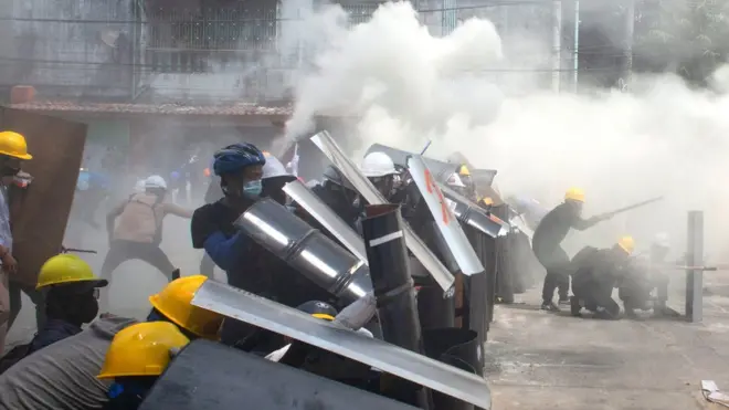 Protesters cover with makeshift shields during an anti-coup protest in Yangon