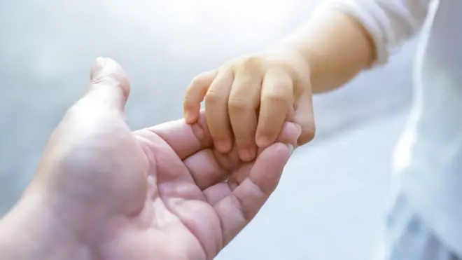 Un niño pequeño toma la manoapostas casasun adulto