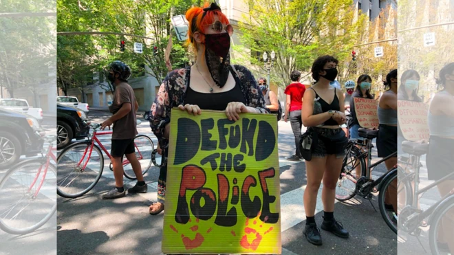Una manifestante con un cartel de "defund the police" (desfinanciamiento a la policía) en Portland el 30 de julio de 2020.