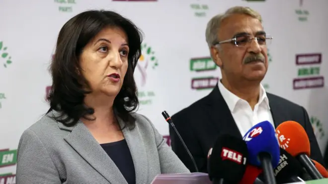 Pervin Buldan ve Mithat Sancar bir kürsüde. Önlerinde mikrofonlar var. Pervin Buldan konuşuyor. 