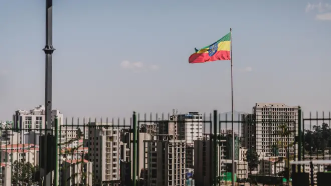ባላለቁ ሕንጻዎቹ እና የሚውለበለብ የኢትዮጵያ ሰንደቅ ዓላማ