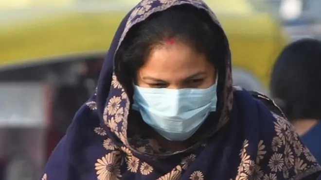 दिल्ली में मास्क लगाए महिला