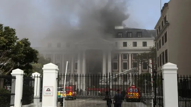 Firefighters work among the smoke after a fire broke out in the Parliament in Cape Town, South Africa, on 2 January 2022