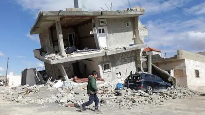 Mtoto akipita karibu na jengo lililoporomoka