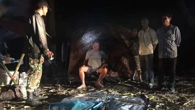 ภาพถ่ายนายเปรมชัย กรรณสูต (นั่งตรงกลาง) ขณะที่ถูกเจ้าหน้าที่เขตรักษาพันธุ์สัตว์ป่าทุ่งใหญ่นเรศวรจับกุมตัว