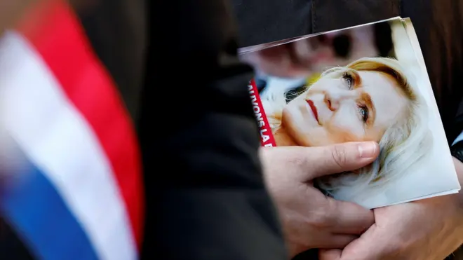 Листовка с изображением Марин Ле Пен в руках человека с французским флагом.