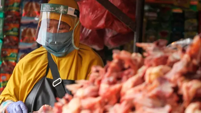 Seorang pedagang daging ayam menggunakan pelindung wajah saat berjualan di Pasar Kemiri Muka, Depok, Jawa Barat, Kamis (30/04