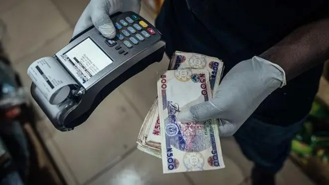 Pesin hold POS machine for hand wit naira notes