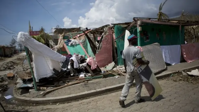 Un hombre carga una pancarta electoral en Les Anglais, Haití, después del paso del huracán Matthew.
