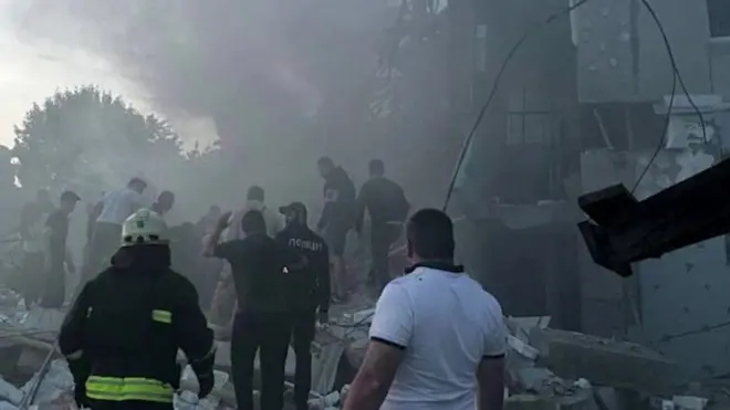 Screengrab of footage that shows rescuers in Ukraine looking through a smoking, ruined building
