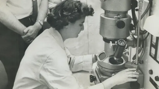 Atkinson Charitable Foundation gift of $36;300 to the Ontario Cancer Institute in Toronto was denoted to duplicate this powerful electron microscope. It is urgently needed to aid research. It is urgently needed to aid research. At miscroscope is Mrs. June Almeida. Behind her Dr. Donald Parsons; in back is Dr. Arthur W. H. (Photo by Norman James/Toronto Star via Getty Image