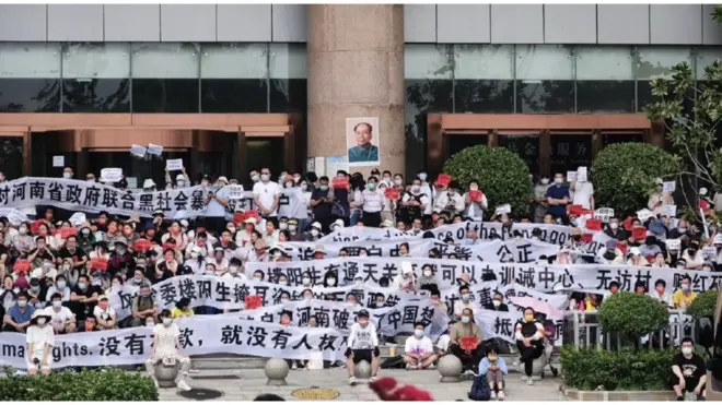 数以百计的村镇银行储户与警方对峙，并遭到身份不明的人士殴打。