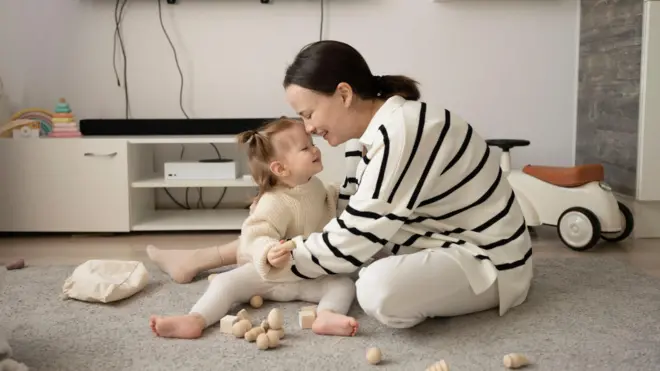 أم وطفلتها تلعبان في غرفة المعيشة