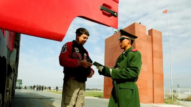 A police officer (R) checks a passport in Xinjiang (File picture October 2005)