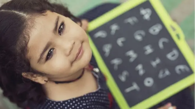 పలక మీద ఏబీసీడీలు దిద్దుతున్న ఓ బాలిక