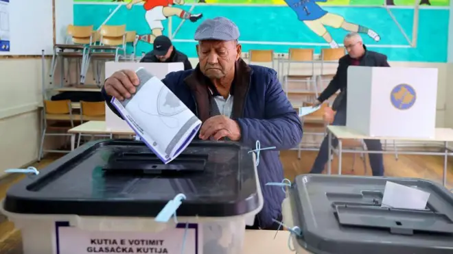 Stariji čovek ubacuje glasački listić u plastičnu kutiju