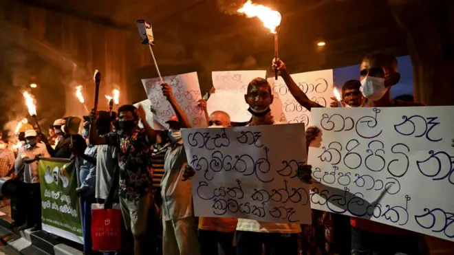 Sri Lanka's main opposition activists hold torches during a demonstration to denounce the shortage of cooking gas, kerosene oil and a few other commodities as the country faces a major foreign exchange crisis, in Colombo on January 5, 2022.