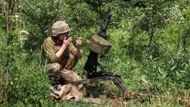 A Ukrainian service member is pictured near an automatic grenade launcher at a position on the front line in Donbas