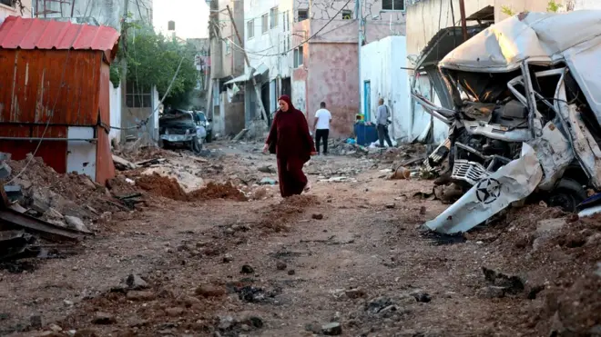 A Palestinian walks amid debris on a destroyed street after an Israeli army raid in the West Bank city of Jenin, on 5 July 2023