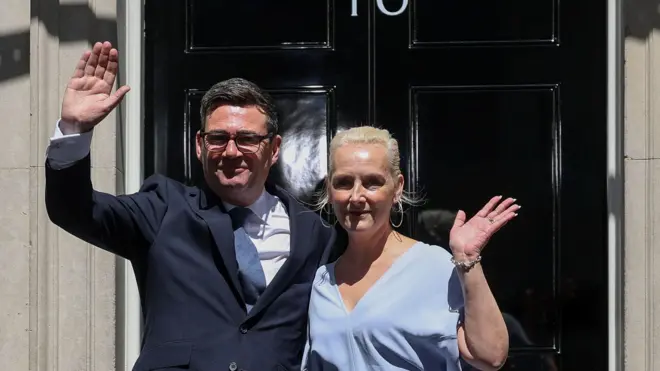 Nowo mianowany premier Wielkiej Brytanii, Andy Burnham, stoi przed siedzibą przy Downing Street 10 tuż po objęciu urzędu, machając zebranym. U jego boku stoi żona, Marie-France van Heel. Londyn, Wielka Brytania, 20 lipca 2026 r. Źródło: Reuters/Isabel Infantes.