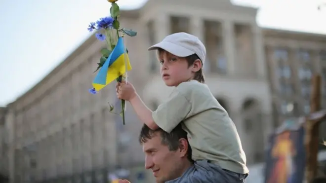 Ўғлини елкасига кўтариб олган украиналик ота