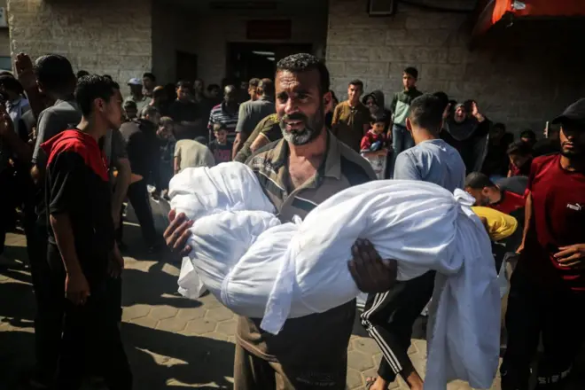 رجل فلسطيني يحمل جثمان قريبه الذي قتل في قصف إسرائيلي لمنزل في مخيم المغازي للاجئين