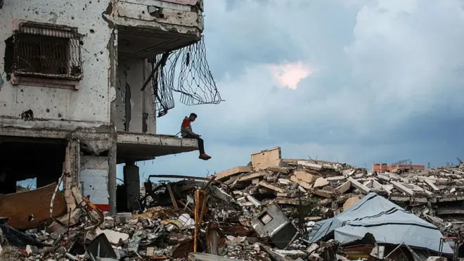 A man sits on the edge a destroyed building in the Al-Saftawi neighborhood, west of Jabalia city in the northern Gaza Strip on December 10, 2025. 