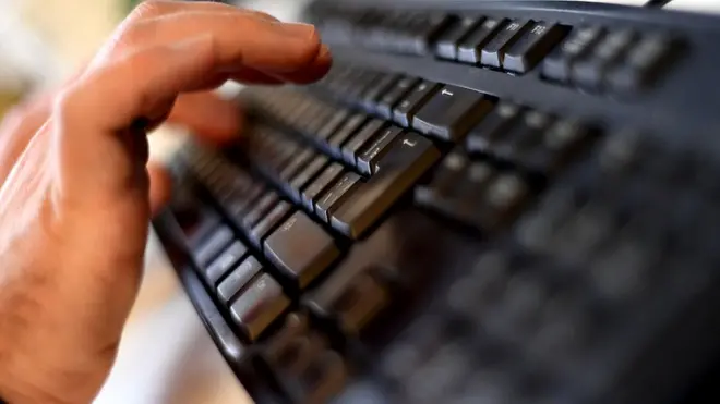 Man's hands typing on a computer keyboard