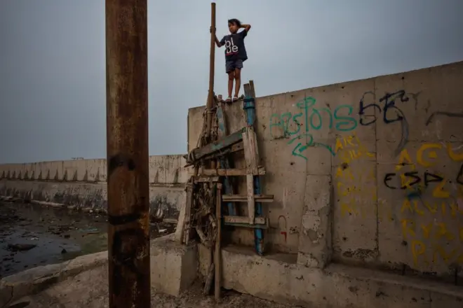 پسری روی دیوار جدیدی که برای محافظت از جاکارتا در برابر بالا رفتن سطح دریا ساخته شده است، راه میرود